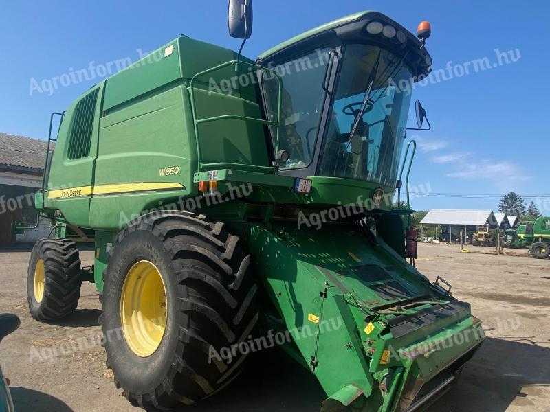 John Deere W650 combine harvester with grain table, with transport wagon
